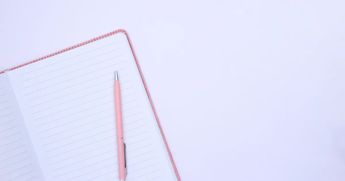 Cuaderno de líneas abierto con un bolígrafo rosa encima sobre fondo claro