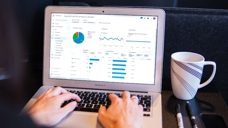Persona trabajando en un portátil con datos de marketing digital en pantalla en entorno oscuro